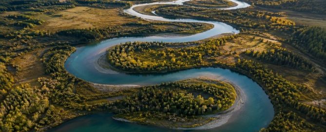 A winding river flowing through a natural landscape, illustrating how repeated behaviours create familiar pathways over time.