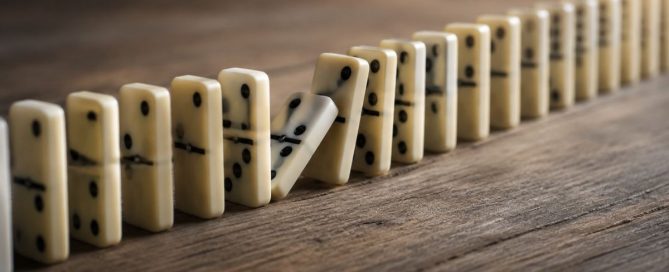 A line of dominoes with one beginning to fall, symbolizing how repeated behaviours can gradually progress from a habit to an addiction.