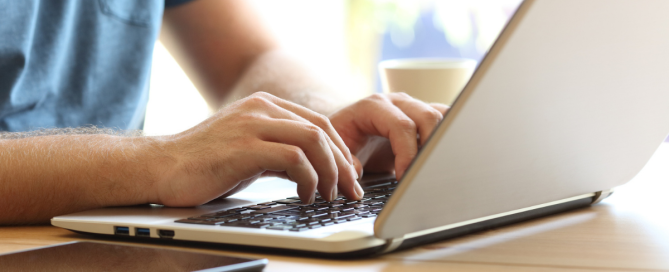 Person researching addiction recovery resources on a laptop while taking notes at a desk.
