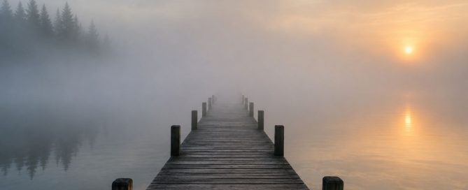 A wooden dock disappearing into dense morning fog over a calm lake, symbolizing the journey from sobriety into deeper emotional recovery.