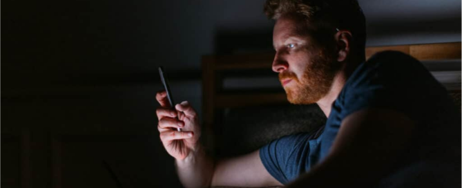 man sitting in the dark looking at his phone late at night reflecting on porn use