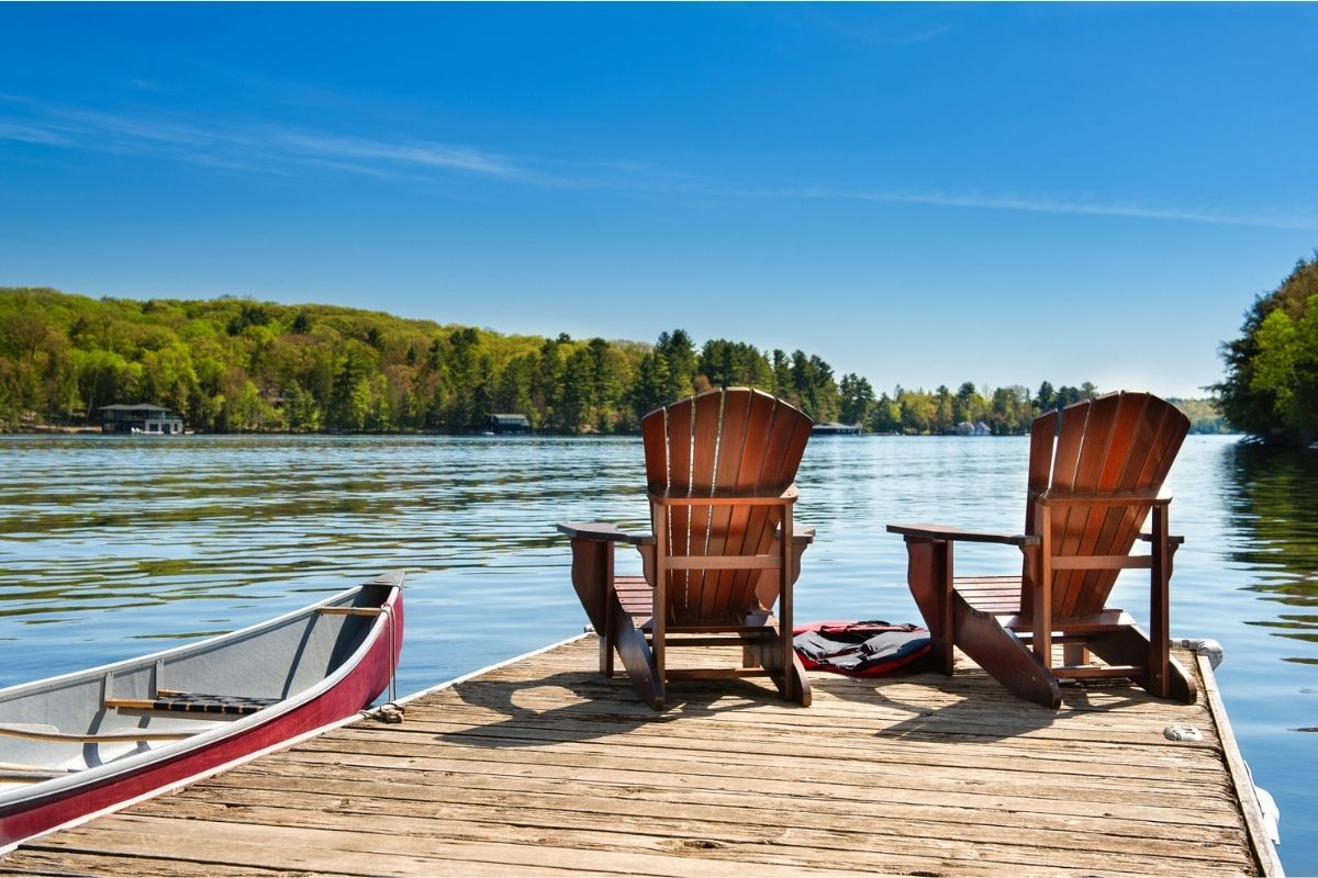 Peaceful lakeside dock with two chairs and a canoe representing reflection, healing, and long-term recovery from compulsive sexual behaviour.