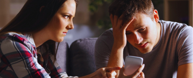 woman confronting partner after discovering porn addiction on phone