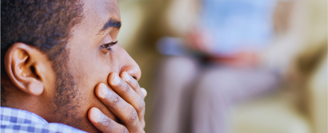 Man sitting with head in hands, showing distress and internal conflict related to compulsive sexual behaviour