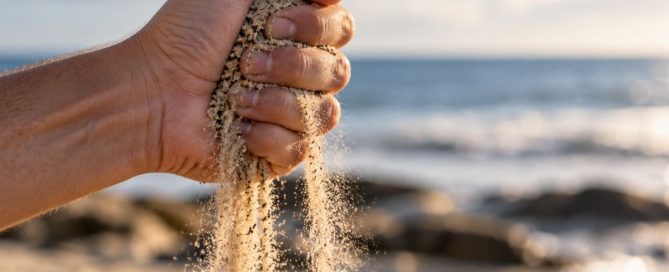 A tightly clenched hand holding sand as it slips through the fingers, symbolizing the difficulty of trying to control everything.