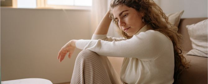 Woman sitting alone looking concerned and reflective, representing emotional impact of discovering porn addiction in a relationship